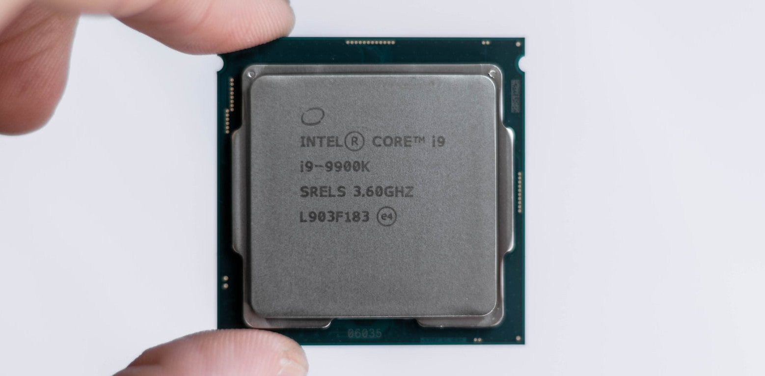 Person holding an Intel i9 CPU chip with his fingers